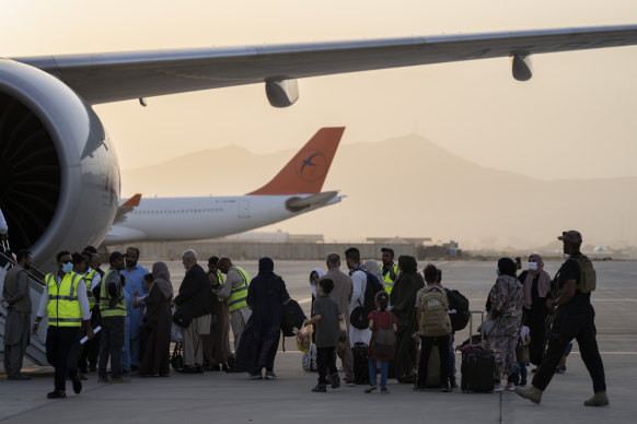 Afghans and foreigners board a Qatar Airways plane to leave Kabul in September 2021.