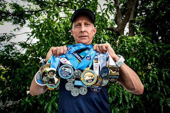 Mark Goodwin with his medals from years of competing in the Sydney Marathon, and one for finishing every major in the world.