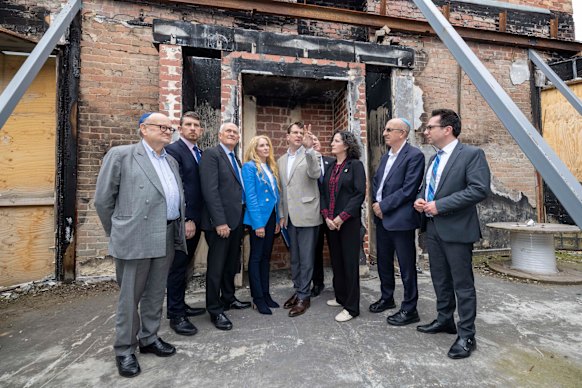 Daniel Aghion (centre) speaks to visitors to the Adass Israel synagogue on the anniversary of its firebombing. 