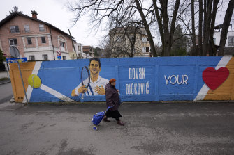 Une femme passe devant une fresque représentant le joueur de tennis serbe Novak Djokovic sur un mur à Belgrade.