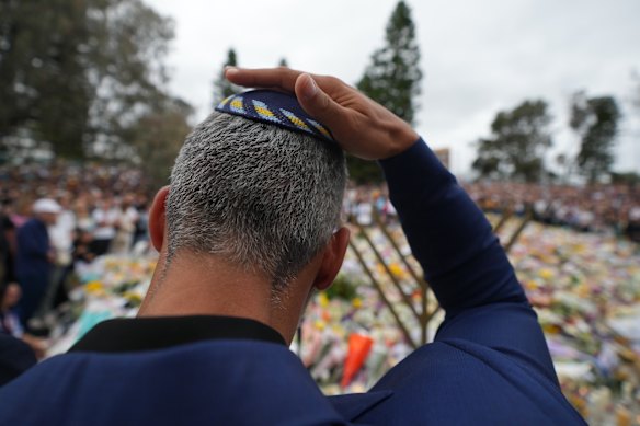 A man mourns during a menorah lighting ceremony at the floral memorial for victims of the Bondi Beach attack.