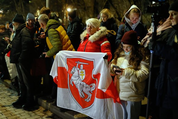 A woman holds an Old Belarusian flag as she awaits released prisoners at the US embassy in Vilnius, Lithuania.