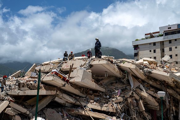 Firefighters and volunteers search for possible victims atop a collapsed building in Caraballeda.