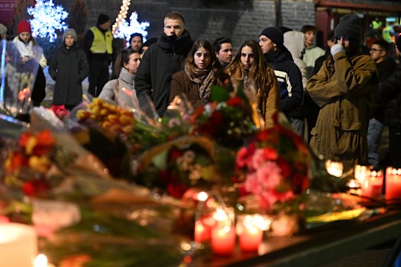 Mourners gather to leave flowers for the victims of the fire.