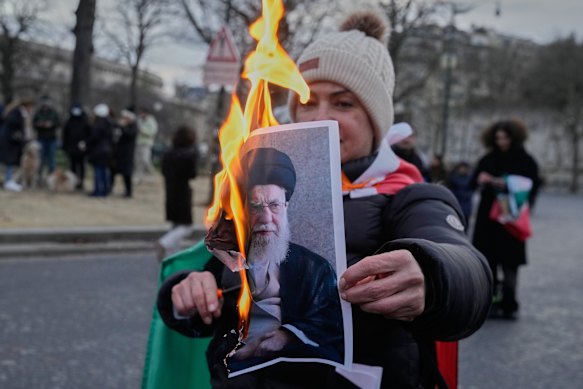 A protester burns an image of Iran’s Supreme Leader Ayatollah Ali Khamenei at a rally in Paris.