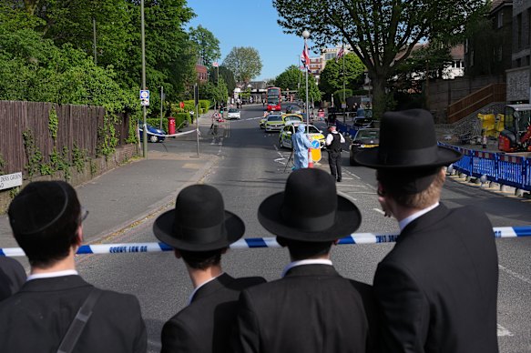 Members of the Jewish community watch on as police search the area.