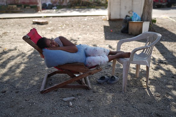 A woman rests close to buildings that collapsed during the earthquakes in La Guaira, Venezuela, Tuesday, July 7, 2026. 