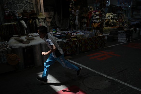A beam of sunlight is cast on a child ras he runs past stores inside the Jinshan market in Altay Prefecture, northwest China's Xinjiang Uyghur Autonomous Region.