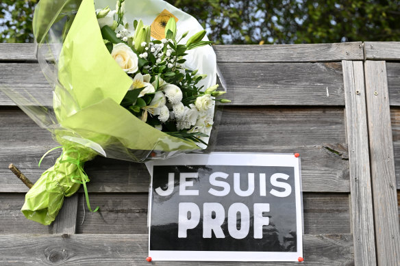Fowers next to a placard reading “I am a teacher” are pictured near the Bois d’Aulne school in Conflans-Sainte-Honorine, outside Paris.