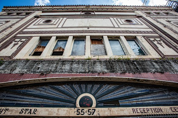 The once grand art deco facade has been reduced to broken windows, crumbling walls and faded signage.