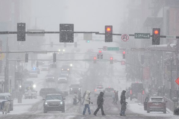 Pedestrians cross the street along Broadway during a winter storm Saturday, Jan. 24, 2026, in Nashville, Tenn.