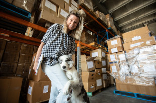 Silvia Hill and her most valuable employee in their warehouse, Luna the Border Collie.