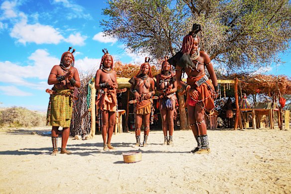 Young Himba women dance next to a village stall.
