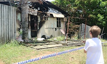 A little boy clings to his pet bird outside his burnt-out home in Margate.