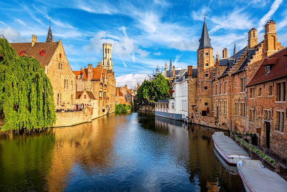 Quieter for tour groups here too. The Rozenhoedkaai canal, historic brick houses and the Belfry in Bruges medieval Old Town, Belgium.