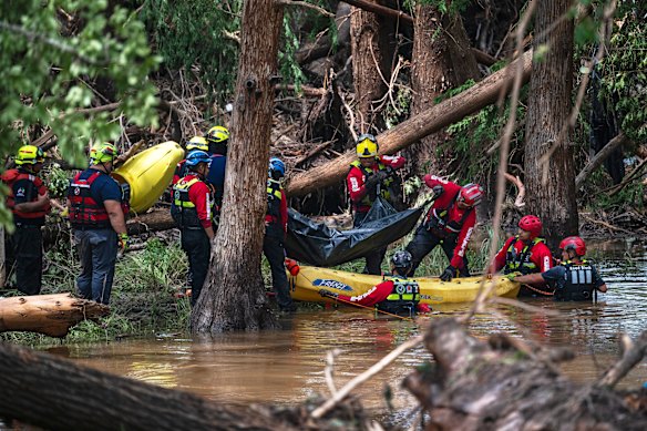 Mexican firefighters load a body into a raft on the Guadalupe River in Texas on Monday.