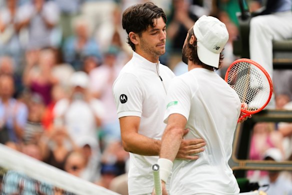 Jordan Thompson meets American Taylor Fritz at the net after retiring from their fourth-round match at Wimbledon.