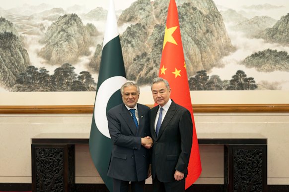 Chinese Foreign Minister Wang Yi, right, poses for photos with Pakistani Deputy Prime Minister and Foreign Minister Mohammad Ishaq Dar in Beijing.