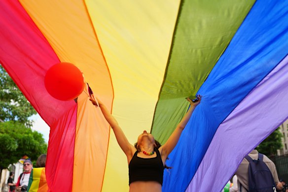 A person gestures under a rainbow flag during the Bucharest Pride Parade, in Bucharest, Romania.