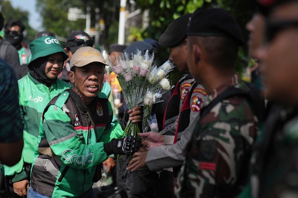 Ride-hailing drivers hand out flowers to police and soldiers during a peace rally in Jakarta on Tuesday.