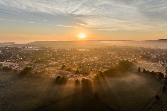 The sun rises over the city of Wehrheim near Frankfurt, Germany, on a foggy morning.