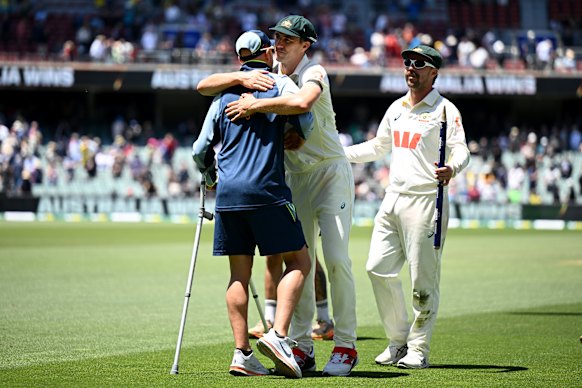 Pat Cummins hugs injured teammate Nathan Lyon while Travis Head waits to do the same after Australia’s win in the third Ashes Test in Adelaide.