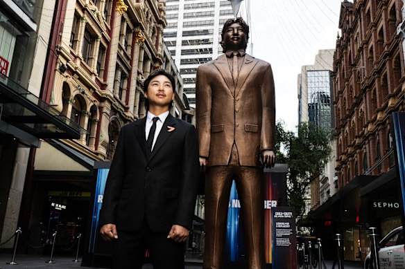 Australian golfer Min Woo Lee standing next to a large statue of himself in Pitt Street Mall at a publicity event for a Call of Duty video game.
