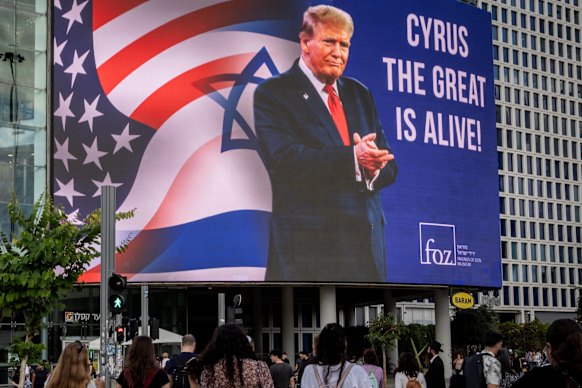 People walk underneath a billboard praising Trump.