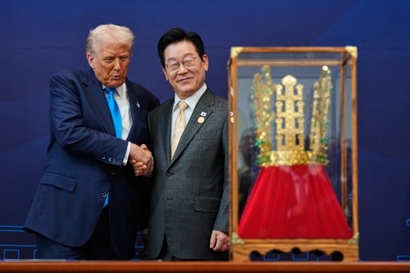 US President Donald Trump shakes hands with South Korean President Lee Jae Myung as he receives a gift of a gold crown and an award of the Grand Order of Mugunghwa in October.
