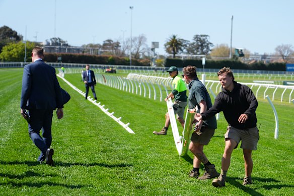 Ground staff move running rails at Caulfield on Saturday to avoid a dangerous stretch of the track.