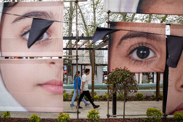 People pass an art installation featuring portraits of some of the Minab school girls killed in an apparent US strike in February, on April 12, 2026 in Tehran, Iran. On April 8 President Donald Trump announced a two-week ceasefire between the US and Iran, conditional on shipping being allowed to resume through the Strait of Hormuz. Peace talks held in Pakistan have since stalled, reportedly over Iran’s nuclear stockpile and continued blockade of the Strait of Hormuz. 