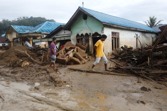Survivors navigate the mud at a village affected by floods in Batang Toru.