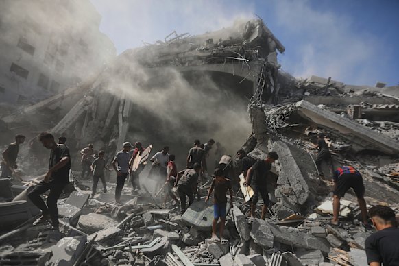 Palestinians search for wood to sell or use for cooking amid the rubble of a building in Gaza City.