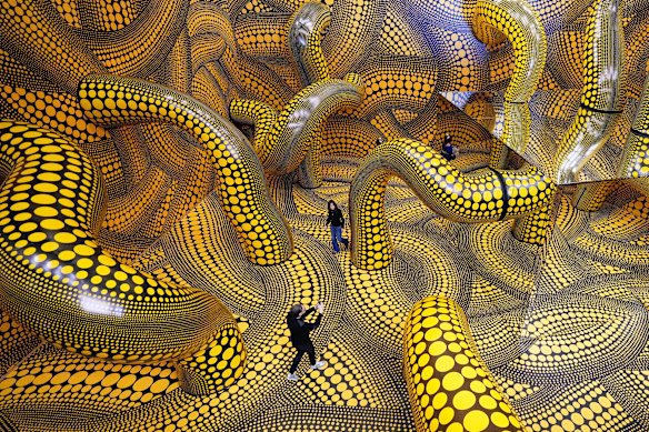 People walk through the artwork ‘Infinity Mirrored Room’ during a preview of the new major exhibition of legendary Japanese artist Yayoi Kusama at the Museum Ludwig in Cologne.