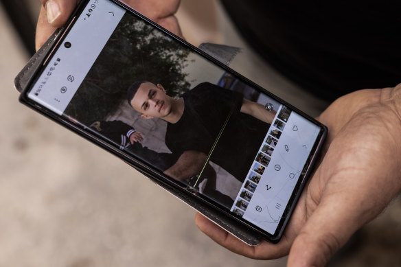 Mustafa Nasser Zandiq, the begetter  of Jihad Nyaz Naser Zandiq, 15, uses his mobile telephone  to amusement   a  photograph   of his son.