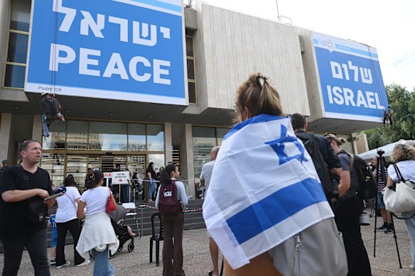 Workers put up pieces of a huge sign that reads, “Peace Israel” in English and in Hebrew on a building in hostage square on Sunday.