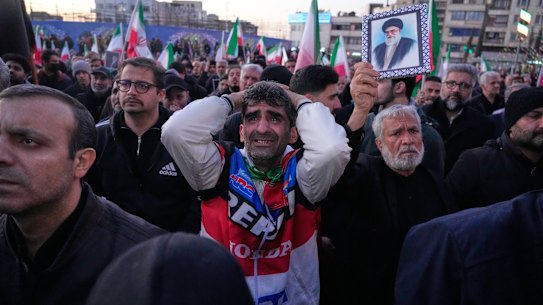 Government supporters mourn during a gathering after state TV officially announced the death of Iranian Supreme Leader Ayatollah Ali Khamenei, shown in the poster, in Tehran, Iran, on Sunday, March 1, 2026.