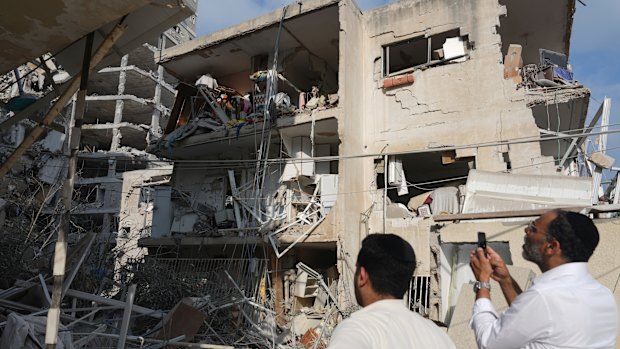 People inspect a destroyed building that was hit by a missile fired from Iran, near Tel Aviv.