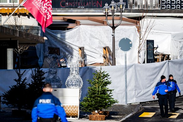Police officers inspect the area where a fire broke out at Le Constellation bar.