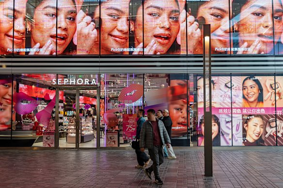 人々は、フランスの美容製品の小売業者であるセフォラの旗艦の北京店を通り過ぎます。
