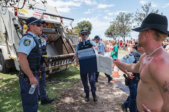 Police confiscate alcohol from partygoers at the beach, which is an alcohol-free zone, on Christmas Day in 2023.