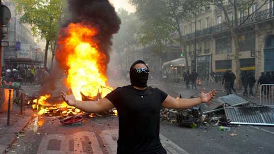 A protester gestures in front of a burning barricade during a demonstration near Place de la République.