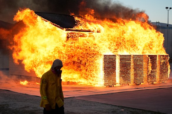 A wildfire researcher walks in front of an accessory dwelling unit burning during an experiment at the Institute for Business &amp; Home Safety centre Richburg, South Carolina.