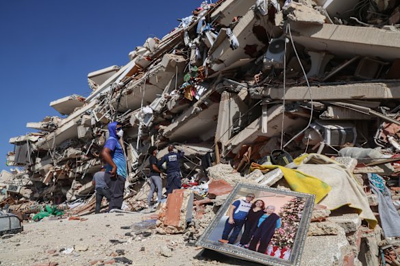 People and rescuers search for victims amid the debris of a building in Caraballeda.