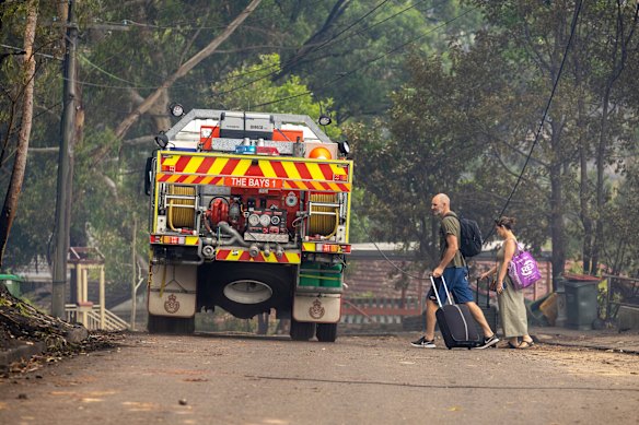 Mike and Katie Greene leave the fire-affected area after retrieving some belongings from their just-completed home which survived the Koolewong bushfire. 