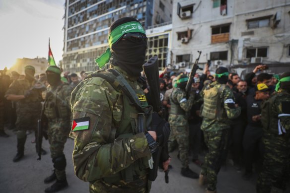 Qassam Brigades fighters control the crowd as Red Cross vehicles manoeuvre to collect Israeli hostages.