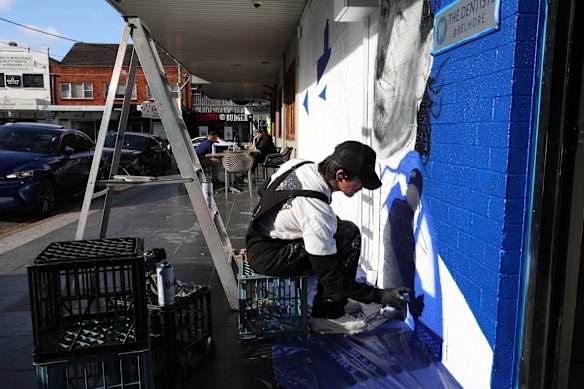 Artist Sid Tapia working on a mural  of legendary Canterbury Bulldogs player Terry lamb, outside Jobel’s Cafe.