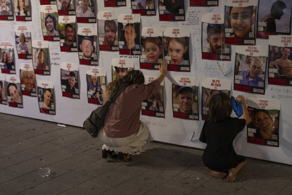 À Tel Aviv, une femme touche des photos d’Israéliens disparus et retenus captifs à Gaza.