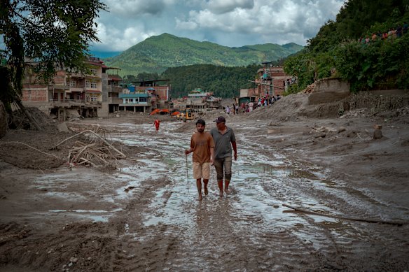 Residents walk along a muddy road following the flash floods in Trishuli, Nepal.