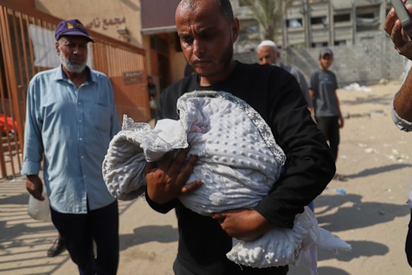Ahmed Abu Halib carries the body of his five-month-old baby, Zainab, who died from malnutrition-related causes, according to the Nasser hospital.